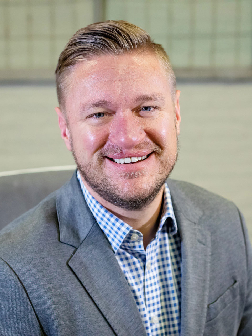 after2-scaledV2 A smiling middle aged man, with a healthy smile, wearing a suit and sitting in a chair.