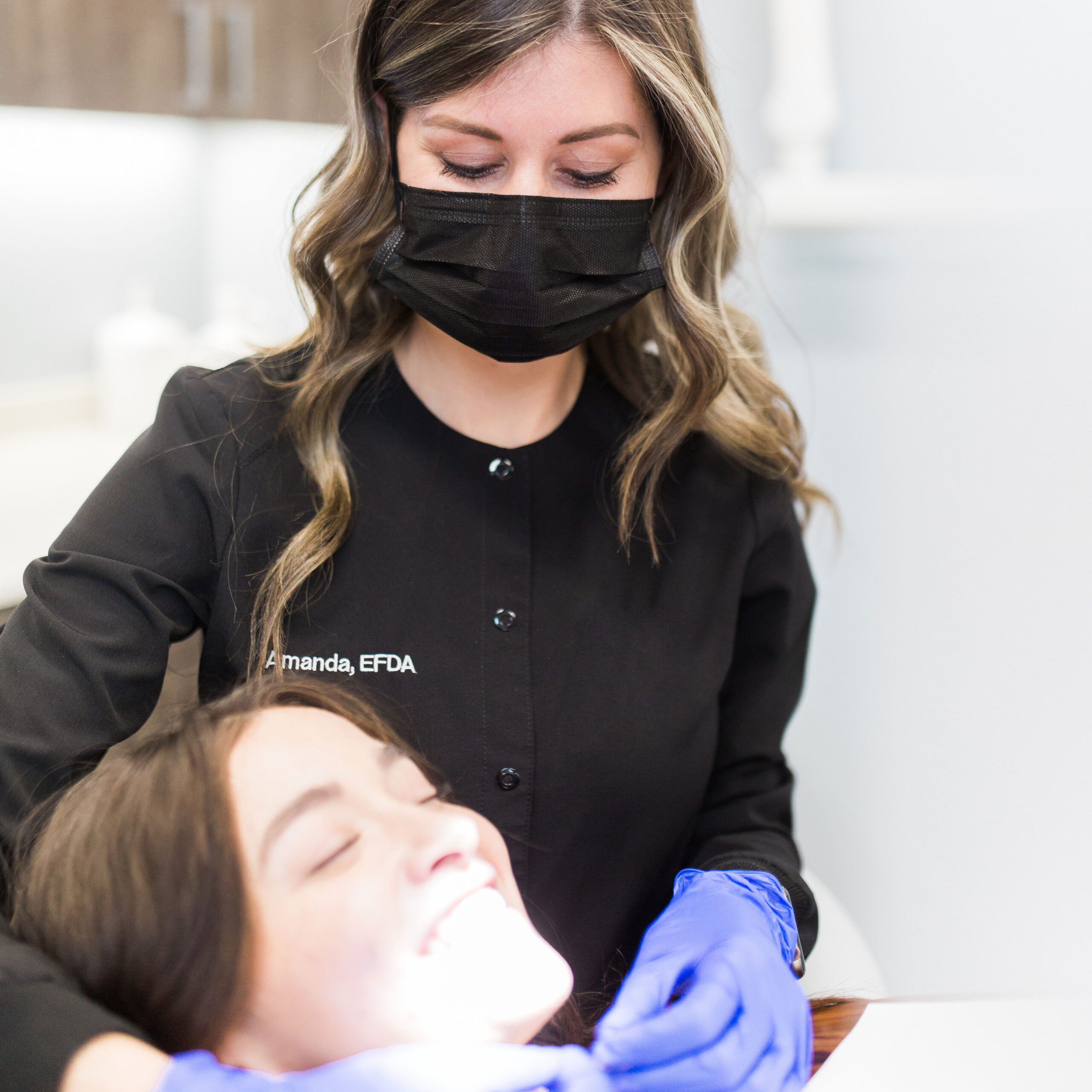 Amanda, the clinical lead at Urbana & Darby Dental Smiles Darby office, preforming an exam on a smiling patient.